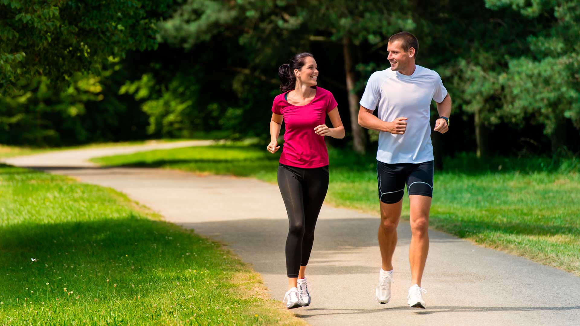 Hombre y mujer jóvenes corriendo en un parque - HDI SEGUROS